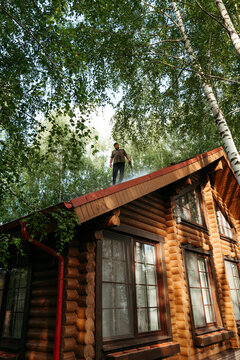 Man Balancing on the Roof of a Log Cabin