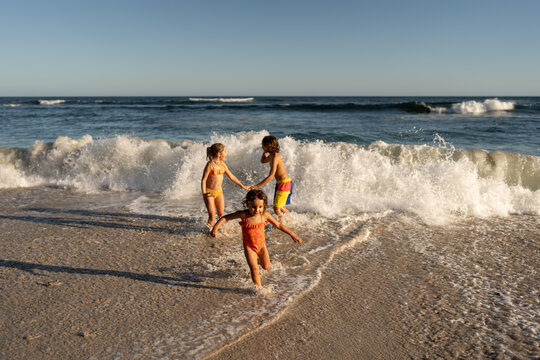 Kids waiting for the big waves at the beach and jumping