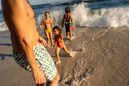 Kids waiting for the big waves at the beach and jumping