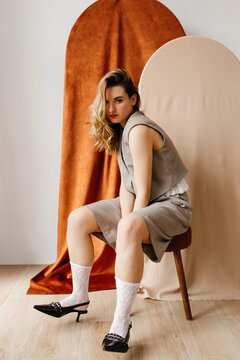 Fashion model posing on stool with velvet backdrop