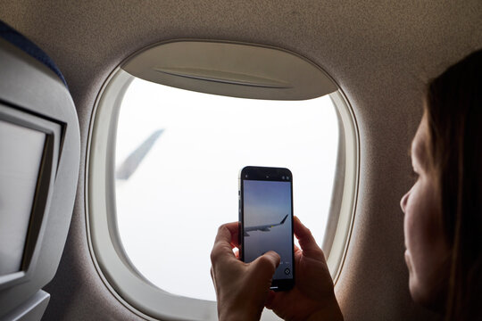 A woman taking a photo  of a plane wing with her phone