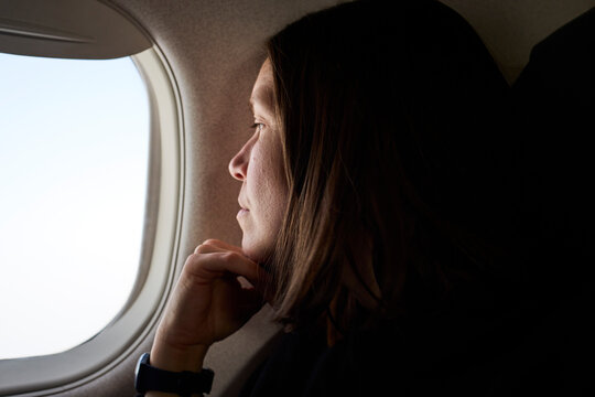 A woman looks outside airplane window