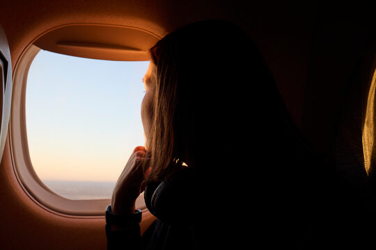 A woman looks outside airplane window