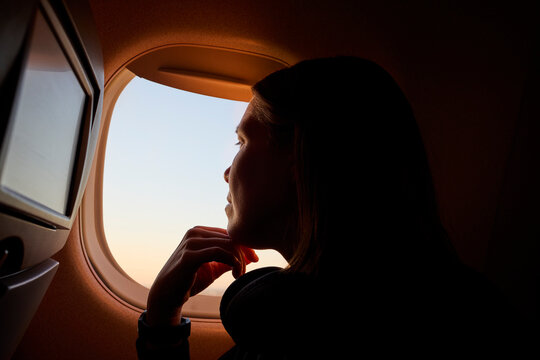 A woman looks outside airplane window