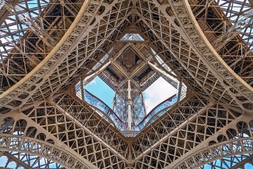 A stunning low-angle view of the Eiffel Tower in Paris captures its intricate iron lattice structure. This iconic landmark represents architectural brilliance and charm in the heart of Paris.