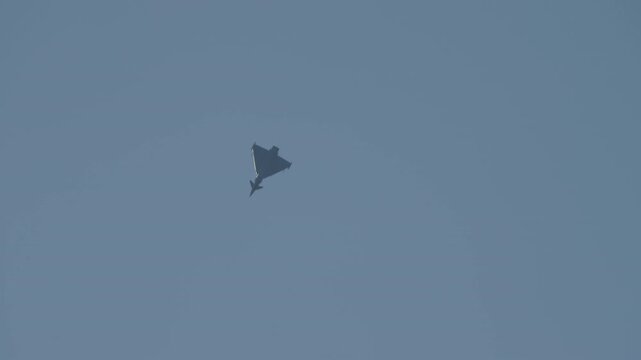 LUQA, MALTA - SEPTEMBER 28, 2025: A Dassault Rafale fighter jet soars through the sky, performing impressive aerobatic maneuvers. Filmed from below, the delta-wing aircraft twists and turns against a