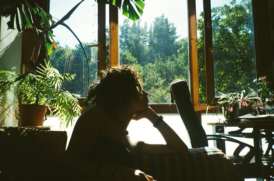 Woman relaxing by sunny window with plants