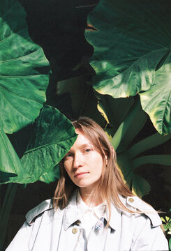 Portrait of a woman with long hair, surrounded by large leaves 