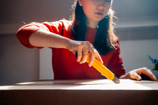 Person using box cutter to open cardboard package