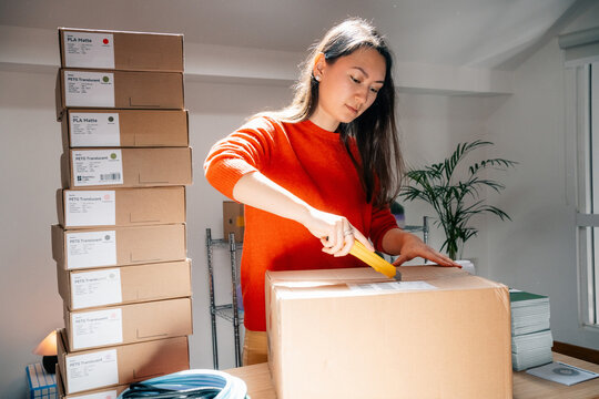 Person opens large cardboard package beside stacked boxes