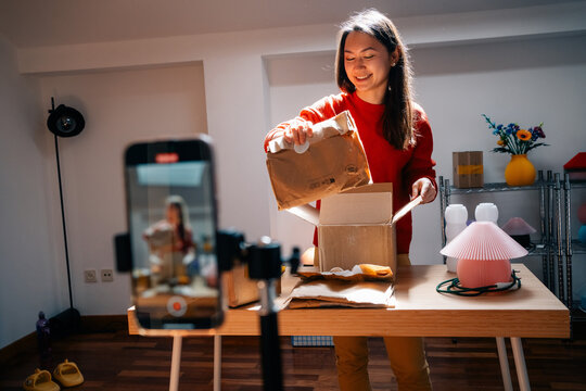 Woman smiles while showing product during unboxing video