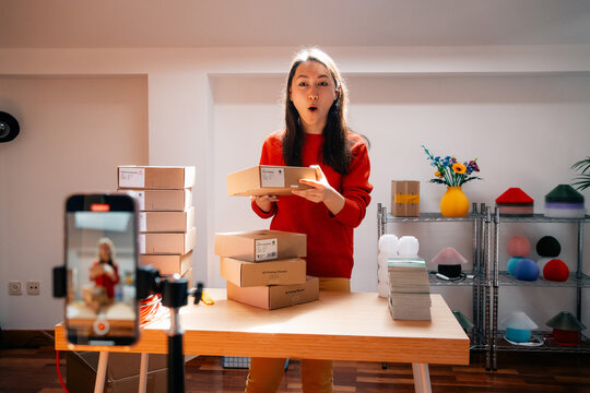 Woman reacts playfully while stacking packages on camera