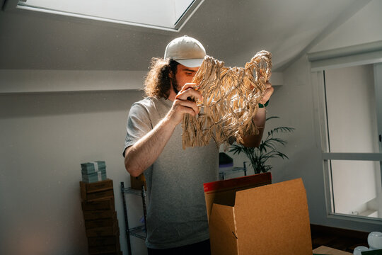 Man inspects shredded paper filler near sunlight