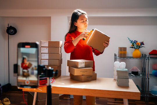 Person opens cardboard package beside stacked boxes