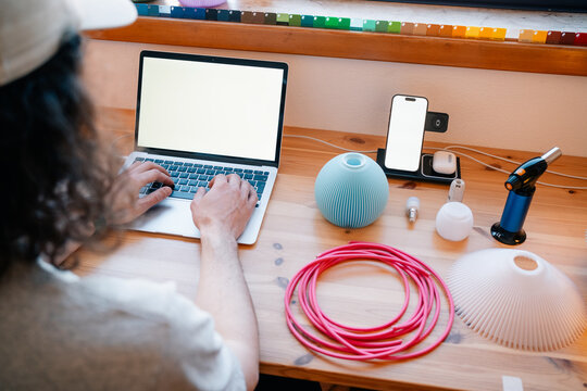 Man types at desk with tech gear and lamp parts