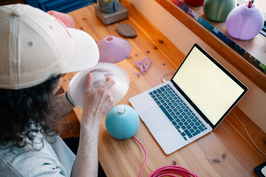 Man assembles lamp parts at wooden desk