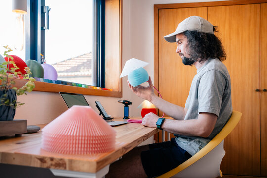 Man examines assembled lamp near bright window