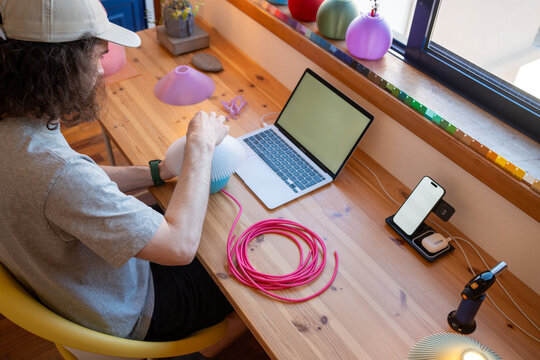 Man assembling lamp near laptop at bright workspace