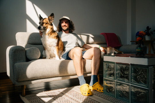 Man sitting on couch with happy dog in cozy living room