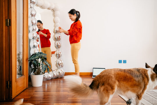 Woman decorating large mirror with textured frame at home