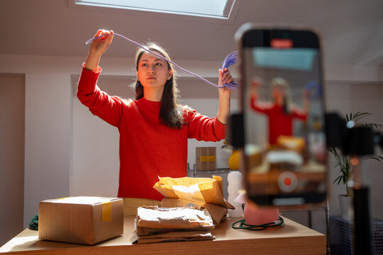 Woman presenting cable while filming with smartphone