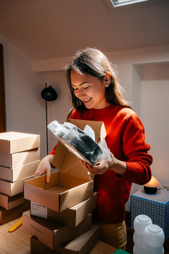 Woman unpacking product from cardboard box with smile