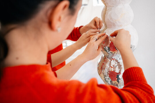 Close-up of hands decorating sculpture with mirror tiles