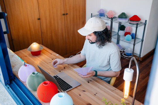 Designer assembling colorful lamps at wooden desk