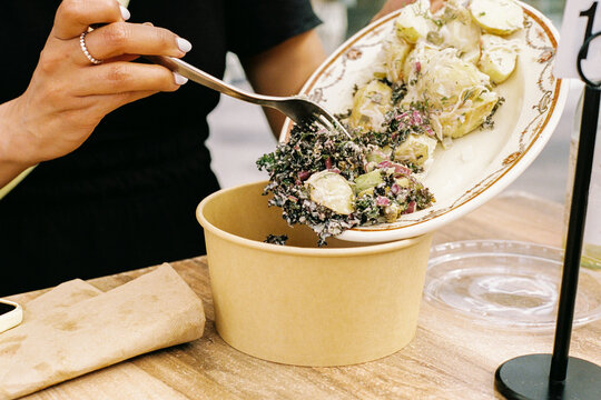 Person serving healthy salad in a recyclable bowl container