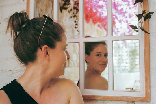 Woman gazing into a mirror reflecting nature