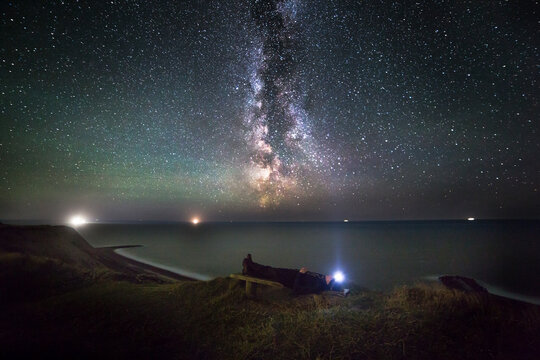 Man rests while watching night sky over sea