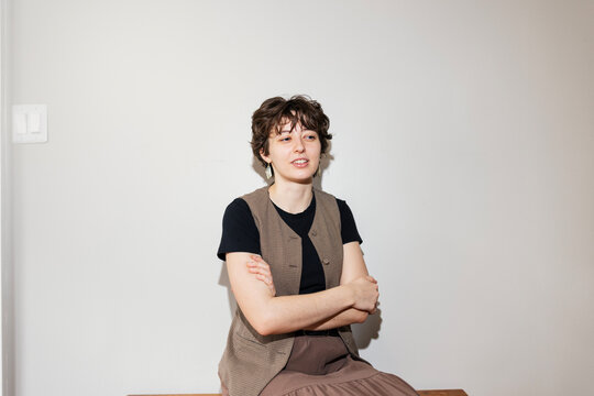 Woman sitting in front of apartment wall with arms crossed