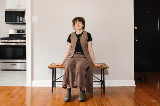 Young Woman sitting on Bench in Empty Apartment