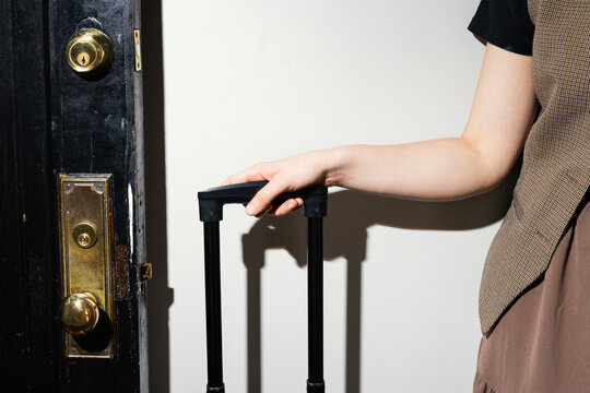 Arm holding Suitcase handle near Old Door