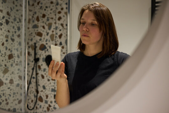 Woman reading skincare cream description