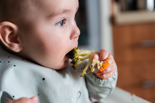 Baby eating healthy broccoli and carrots