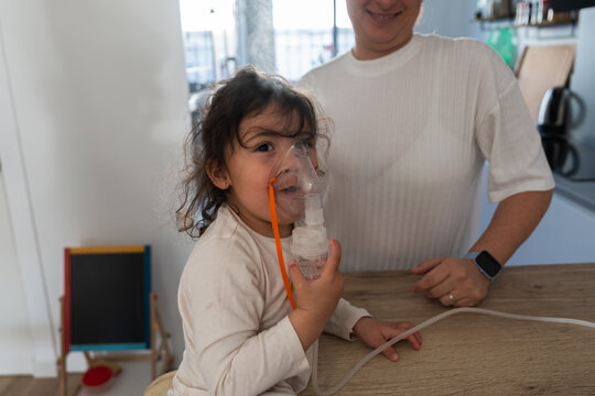 Little girl using inhaler for respiratory therapy at home