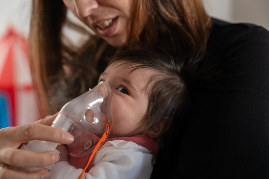 Mother holding baby and giving inhalation treatment