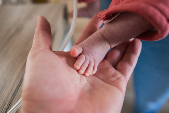 Newborn baby placing feet on parent's hand
