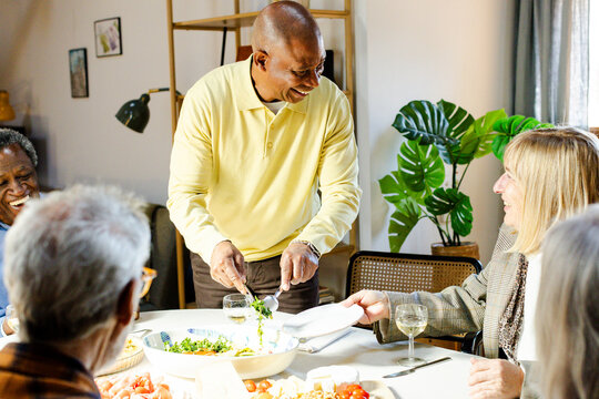 Group of senior friends gathering together around dining table