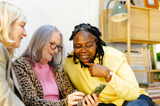 three female friends having fun looking at smartphone