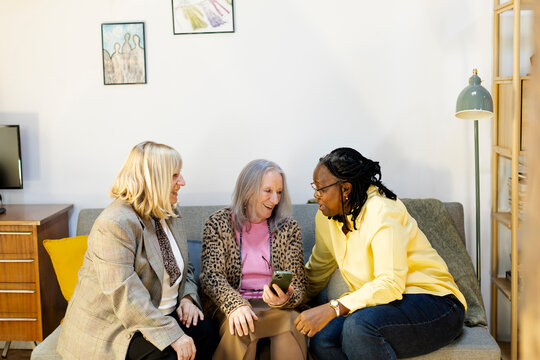 three female friends having fun looking at smartphone