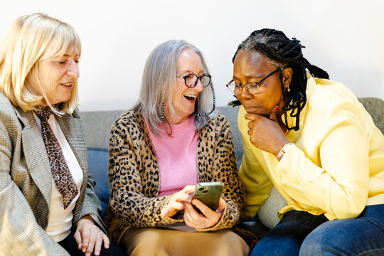 three female friends having fun looking at smartphone