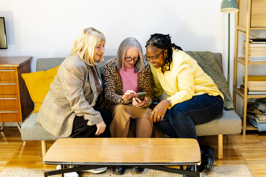three female friends having fun looking at smartphone