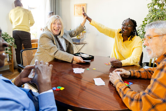 Two senior women celebrating win on cards game at friends home party 