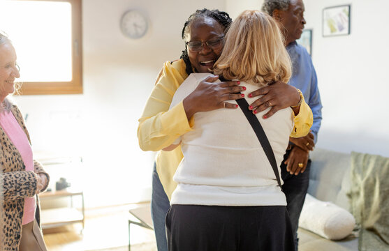 Party of senior friends reunited together hugging and greeting