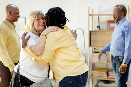 Party of senior friends reunited together hugging and greeting