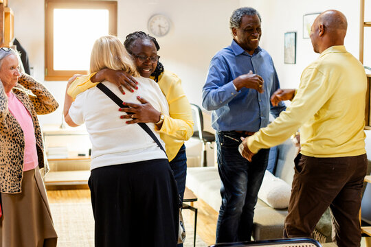 Party of senior friends reunited together hugging and greeting