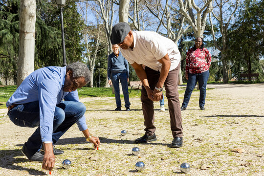 Group of Senior friends playing bocce in park checking score