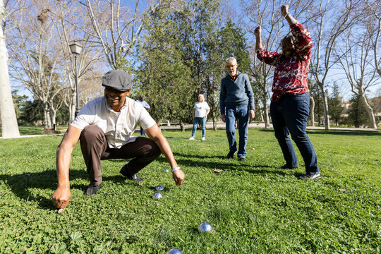 Senior friends playing bocce in park celebrating score
